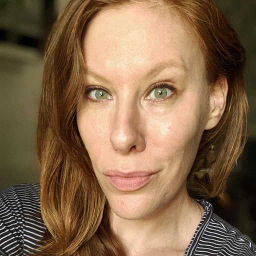Lindsey Obermeier looking at the camera with a neutral expression, wearing a black and white striped top, with a soft background behind her.